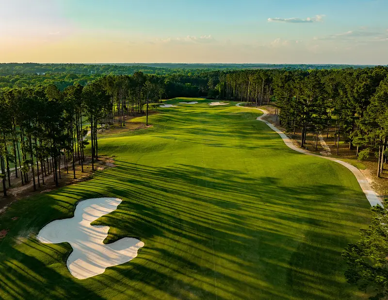 Drone shot of a tree lined fairway with white sand bunkers