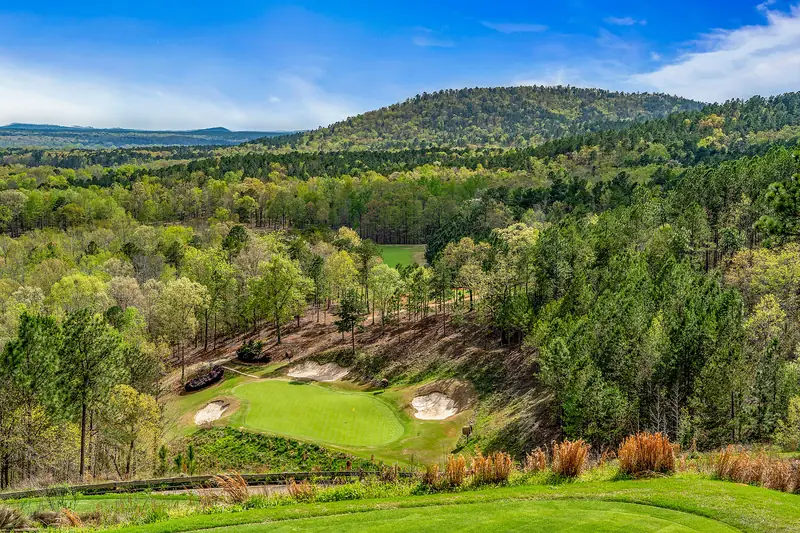 Drone shot of a green tucked into wooded hills