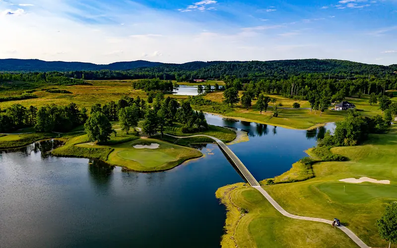 Drone shot of a cart path bridge crossing a lake between golf holes