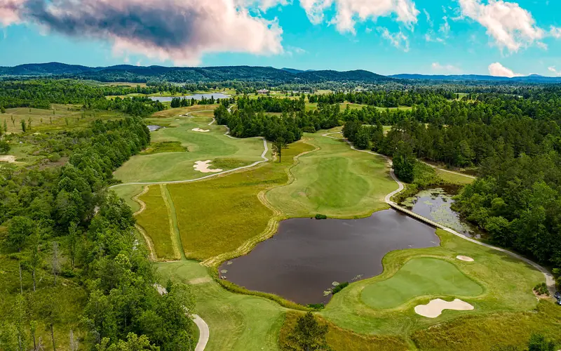Drone shot of greens and bunkers wrapped around a pond