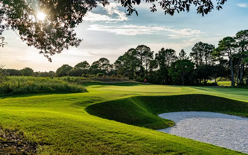 Morning light over a green and a deep white sand bunker