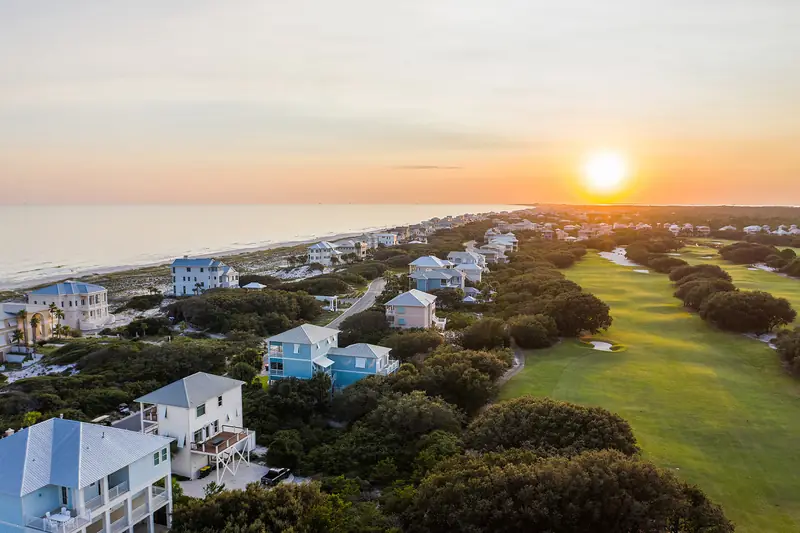 Drone shot of a Gulf Coast golf course at sunset with beach houses and the Gulf in the distance